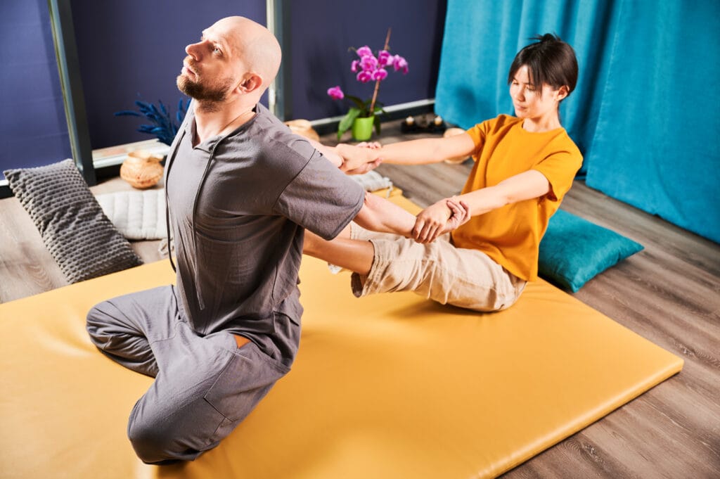 Masajista realizando estiramientos asistidos de masaje tailandés — frecuencia recomendada del masaje Thai en Granada
