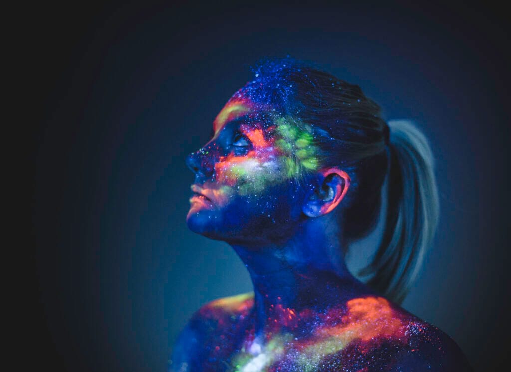 Chica recibiendo una proyección de colores en su cara.