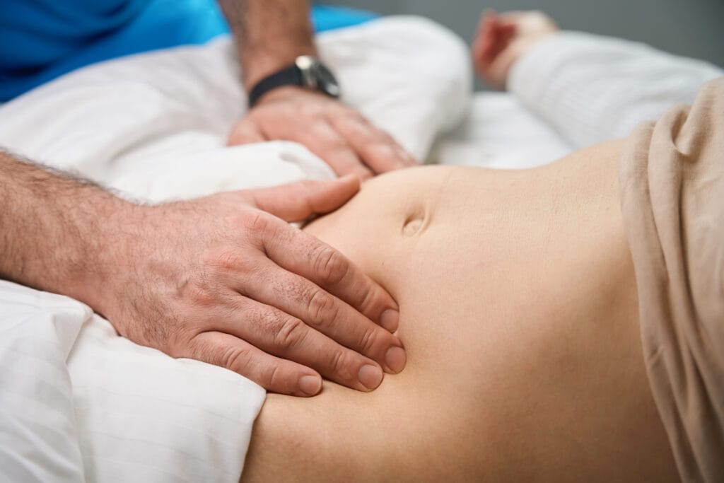 Persona tumbada en camilla durante una sesión de masaje abdominal para la digestión